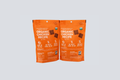 Two orange pet food packages with text on a light gray background